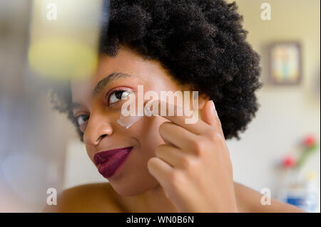 Young woman applying moisturizer to her face Stock Photo
