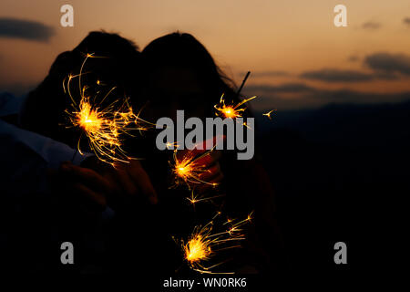 Portrait of young attractive celebrating couple holding firecrackers Stock Photo