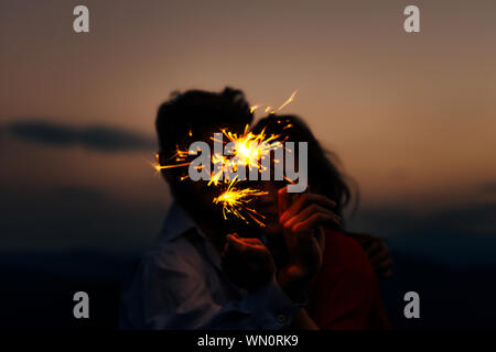 Portrait of young attractive celebrating couple holding firecrackers Stock Photo