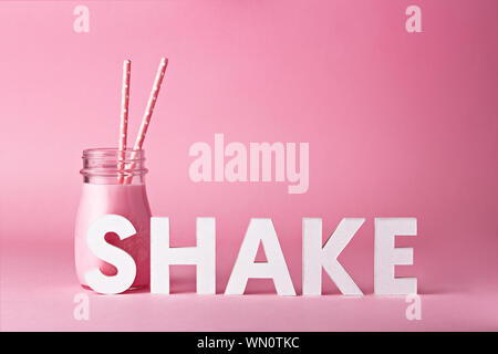 Raspberry Smoothie In Jar With Straws By Text Against Pink Background