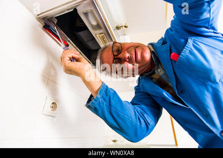 Mature handyman is working with his tools in the kitchen Stock Photo