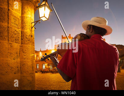 Senior man playing violin at night in Plaza de la Catedral, Havana, Cuba Stock Photo