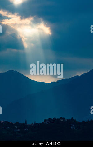 Sunbeams through clouds over mountains in Lombardy, Italy Stock Photo