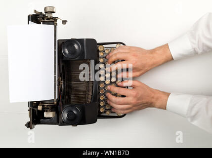Man typing on vintage retro typewriter on white wooden table background top view flat lay from above - journalism, application or writer concept Stock Photo