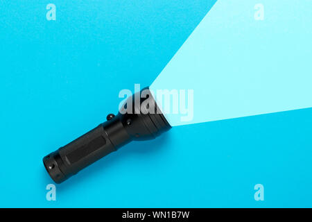 Flashlight or torch lighting up blue background - minimal concept for internet search or direction finding Stock Photo