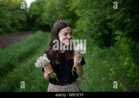 Smiling teenage girl holding dandelions in a field Stock Photo