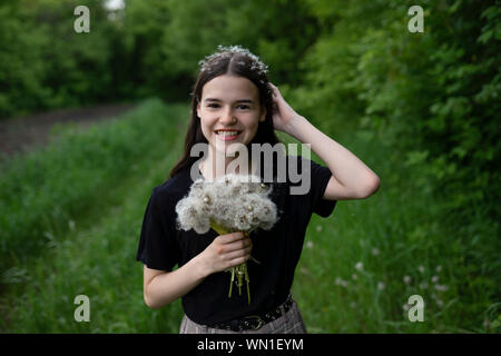 Smiling teenage girl holding dandelions in a field Stock Photo