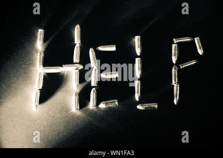 The word 'Help' is spelled out in 9mm bullets with dramatic side light in black and white with mental health concept Stock Photo