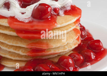 stack of pancakes with cherry and whipped cream topping on plate Stock Photo