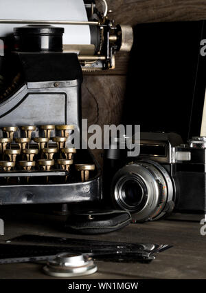 Vintage retro typewriter and analog film camera on brown wooden table background - journalism or writer concept, selective focus Stock Photo