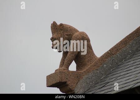 Low angle shot of a creature statue on a building's roof with a clear sky in the background Stock Photo