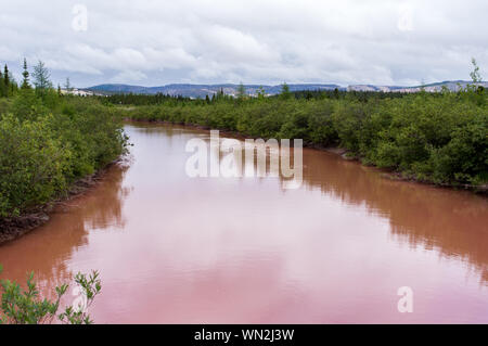 A river coloured red with iron oxide from an iron mine in northern Quebec Stock Photo