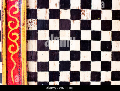 Cabinet doors given a decorative paint job with black and white checks and yellow and red borders. Stock Photo