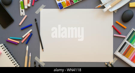 Top view of professional artist workplace with soft pastel colours and painting tools on grey desk background Stock Photo
