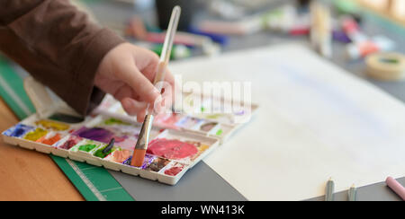 Cropped shot of female artist painting on her project with water colours on grey desk background Stock Photo