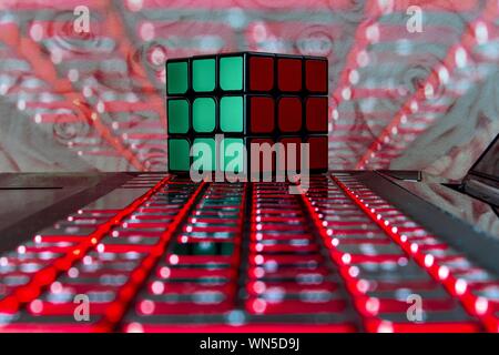 Rubik's cube isolated on a lightful laptop keyboard with a background of red lights and roses Stock Photo