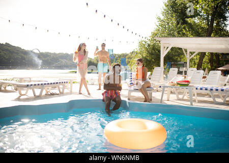 Two couples having amazing pool party on hot summer day Stock Photo