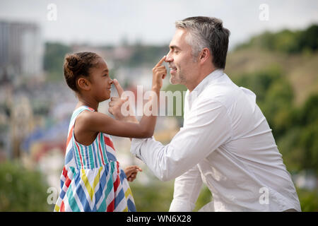 African-American daughter touching nose of her foster father Stock Photo