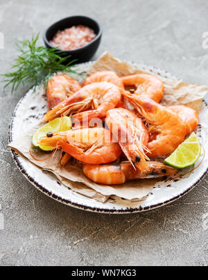 Shrimps in plate with lemons on a grey concrete background Stock Photo