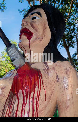 Getting stabbed in the chest at the Hell Garden of Wat Saen Suk in Bang Saen, near Bangkok, Thailand. The garden illustrates warnings of what happens Stock Photo