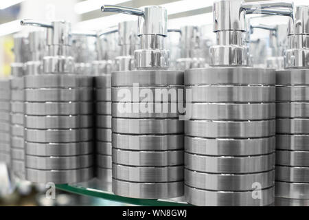Soap dish dispenser for liquid soap, bathroom metal accessories on glass shelve in store close up, toiletries for sale on retail market Stock Photo