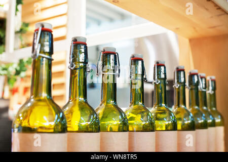 Green glass bottles of wine in row on wooden shelf, bar interior design, preparation of alcoholic cocktails, wine tasting concept, nightlife style Stock Photo