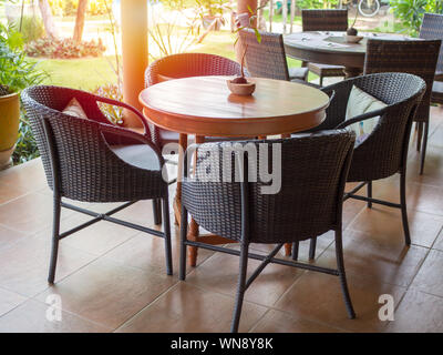 Rattan dining table furniture set on tiles floor in dining room. Stock Photo