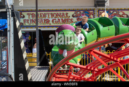 Clacton   United Kingdom 23 August  2019  -:  Young  boys enjoying green caterpillar fairground ride Stock Photo