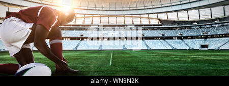 Composite image of african-american man tying shoelaces in rugby pitch Stock Photo