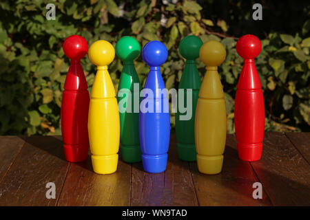 Colorful plastic toy bowling pins on wooden floor close up Stock Photo