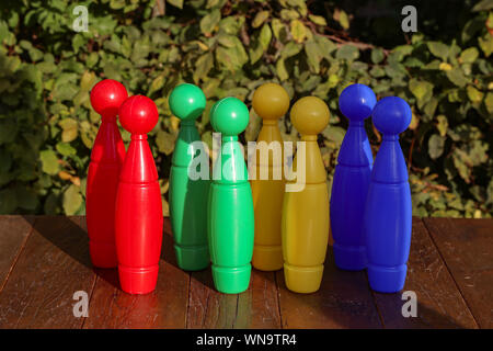 Colorful plastic toy bowling pins on wooden floor close up Stock Photo
