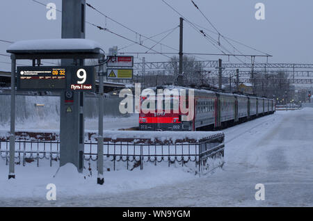 Vitebsky railway station,Saint Petersburg,Russia - January 24, 2019: Red-orange train covered with snow is on the 9th way it is indicated on the lumin Stock Photo