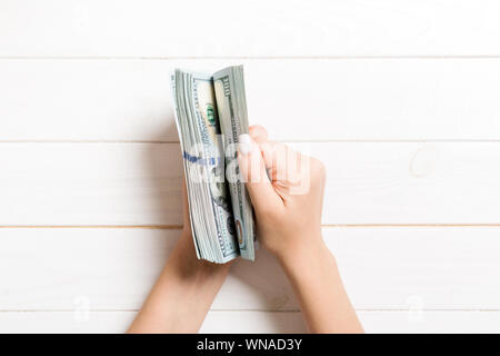 Top view of female hands counting money. One hundred dollar banknotes on wooden background. Salary concept. Bribe concept. Stock Photo