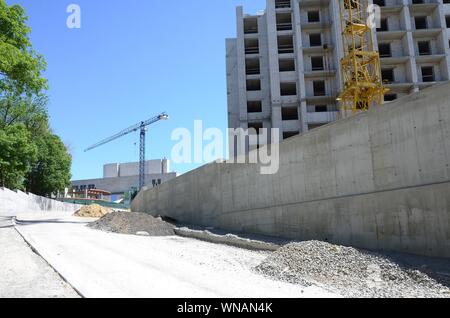 Working tall cranes inside place with tall buildings under construction under a blue cloudless sky Stock Photo