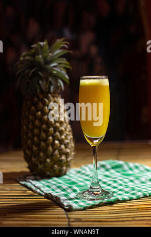 A whole pineapple fruit and a glass of pineapple juice isolated on Dark moody background Stock Photo