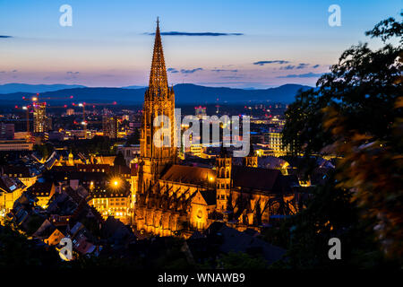 Germany, Cityscape and skyline of freiburg im breisgau with landmark minster or called muenster church in magic twilight atmosphere after sunset at du Stock Photo
