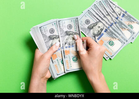 Top view of female hand holding a pack of money on colorful background. One hundred dollars. Business concept with empty space for your design. Charit Stock Photo