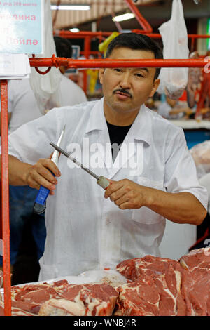 Almaty, Kazakhstan - August 22, 2019: Salesman in the meat section of the famous Green Bazaar of Almaty, Kazakhstan. Stock Photo