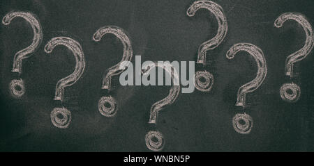 Question marks chalk drawing on blackboard background. Confusion, problem concept Stock Photo