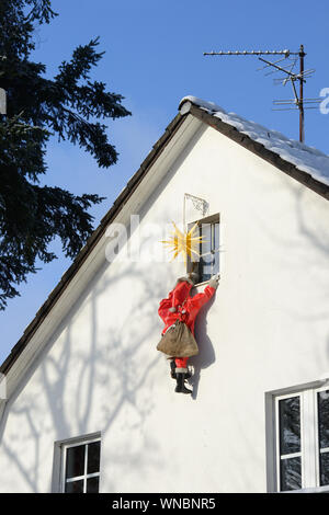 Housebreaker disguised as Santa Clause climbs up a house wall to break in a house through a window Stock Photo