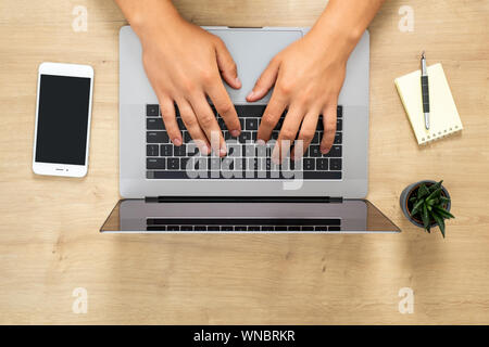Top view human hands working on modern laptop, surfing online, typing a text, browse internet. Flat lay wood office desk table with laptop computer, s Stock Photo