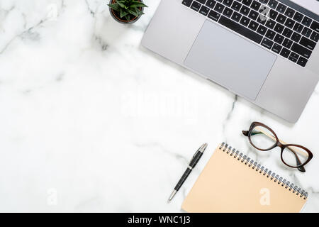Marble office desk table with laptop computer, paper notepad, glasses, succulent plant, stationery. Minimal flat lay style composition, top view, over Stock Photo