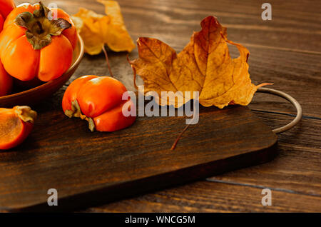 Ripe persimmons on a wooden background. Persimmon variety Fuyu. Close-up. Stock Photo