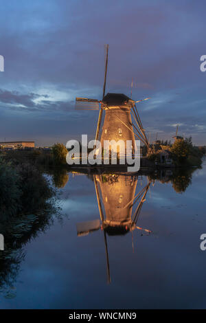 Illuminated windmill reflected on the calm canal water during the bleu hour sunset in Alblasserdam city, Netherlands Stock Photo