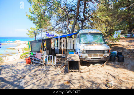 Wild campsite with abandoned old car at forest near sea with beautiful seascape. Summer travel vacation. Freedom lifestyle. Travel destination Greece. Stock Photo