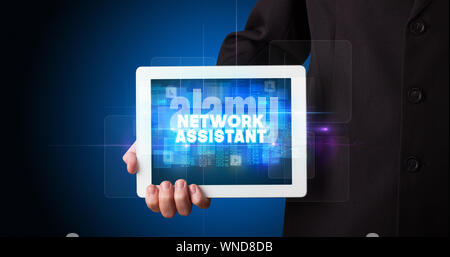 Young business person working on tablet and shows the inscription: NETWORK ASSISTANT Stock Photo
