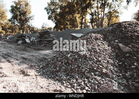 Destroyed old park to build a new. Pile of small stones and broken concrete stabs. Start of construction. Construction materials and crushed stone. Stock Photo