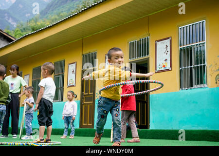(190906) -- CHONGQING, Sept. 6, 2019 (Xinhua) -- Students of nursery class play at Lianhua Primary School of Luzi Village, Chengkou County, southwest China's Chongqing Municipality, Sept. 3, 2019. Mu Yi, a 25-year-old PE teacher from Chongqing Municipality, offers a week-long volunteer teaching service and works with a local teacher Tao Yao in this remote village. In the school where only two second-grade students and 18 preschool children study, Mu Yi and Tao Yao also do other jobs as principals, cleaners, cooks and repairwomen. Mu Yi teaches children sports, art and music and tells them abou Stock Photo