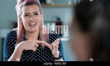 Two Women Having Conversation At Home Using Sign Language Stock Photo