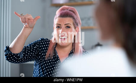 Two Women Having Conversation At Home Using Sign Language Stock Photo